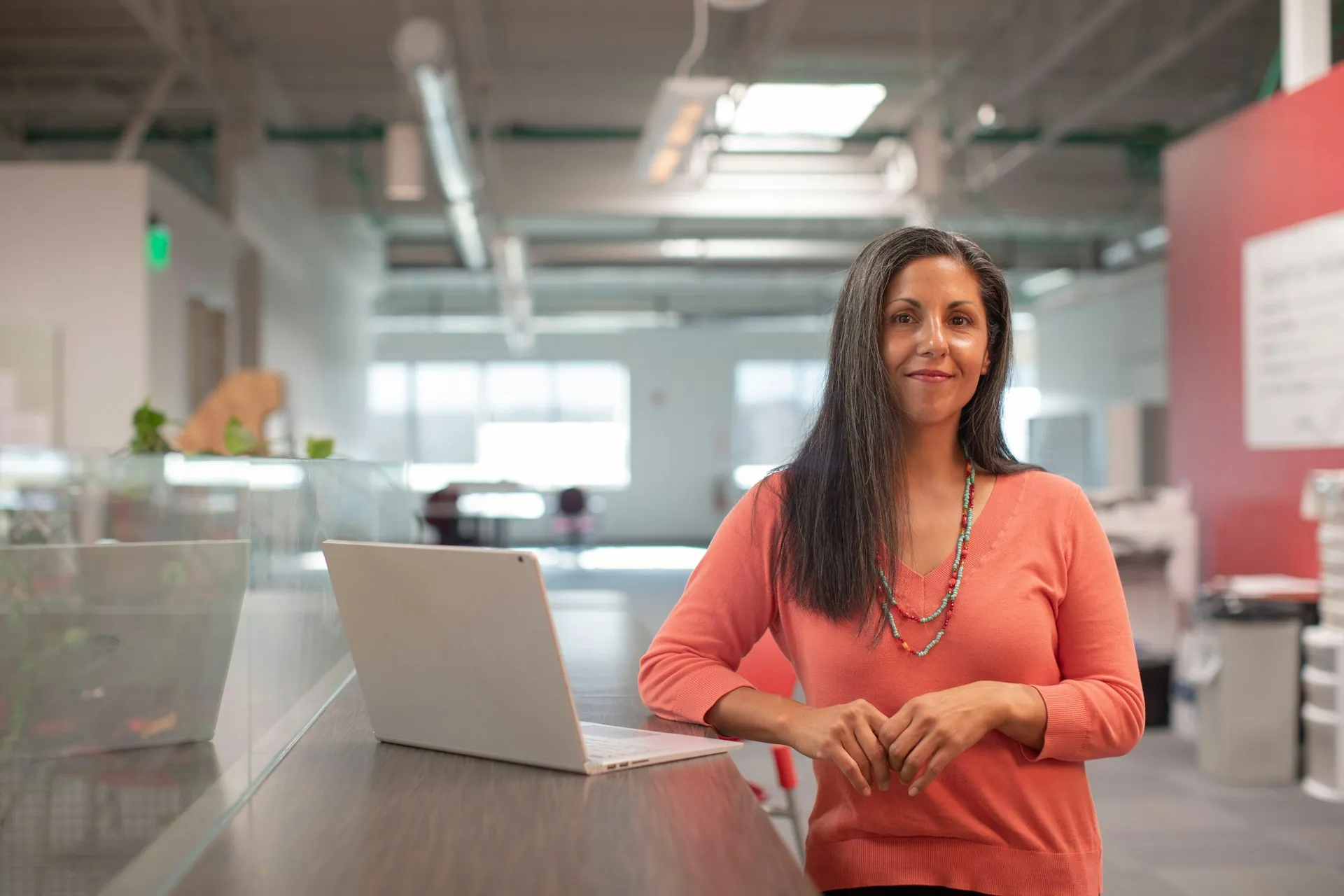 Woman in orange shirt working at a table with a laptop