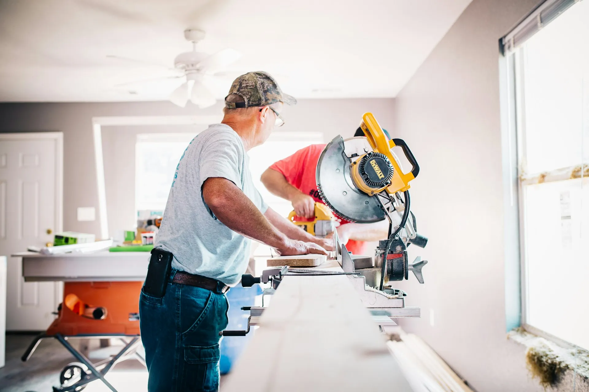 Tradesperson cutting wood at a miter saw on a job site